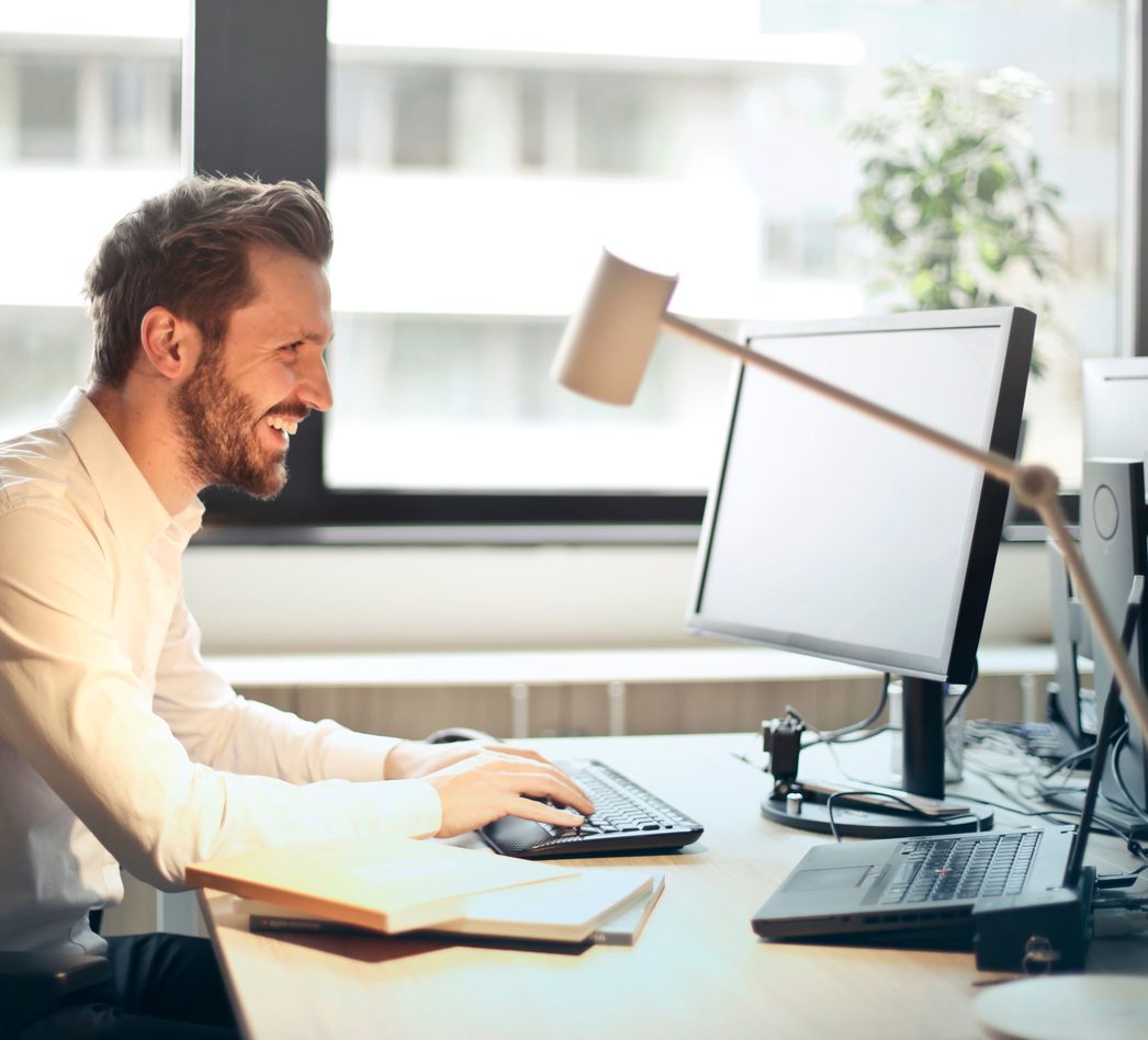 Smiling professional working at a desk with two monitors
